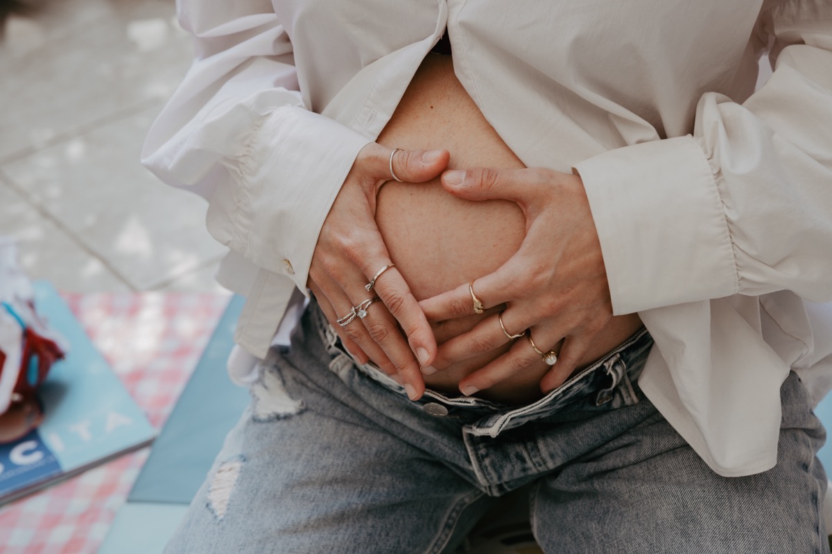 Mani a cuore sulla pancia — fertilità e amore