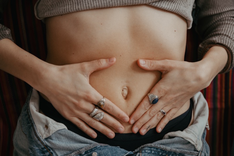 Mani a cuore sulla pancia — connessione con il proprio corpo